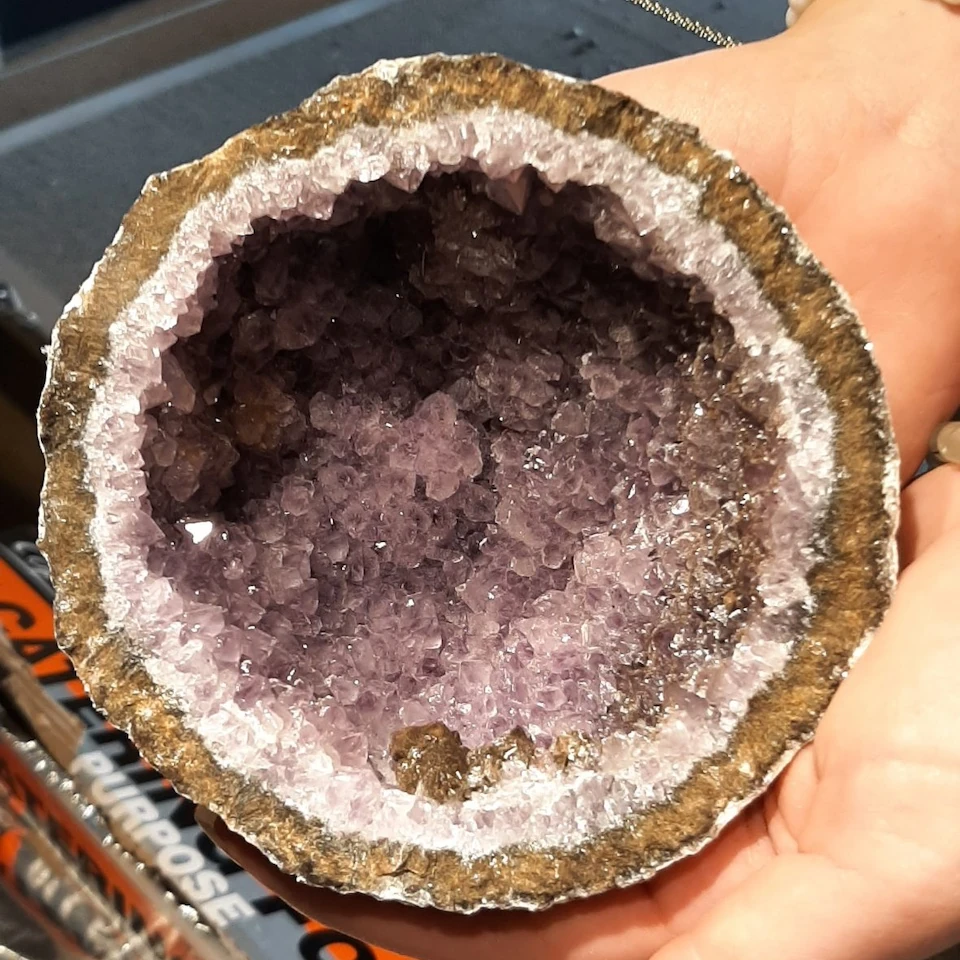 A freshly cracked amethyst geode held in hand