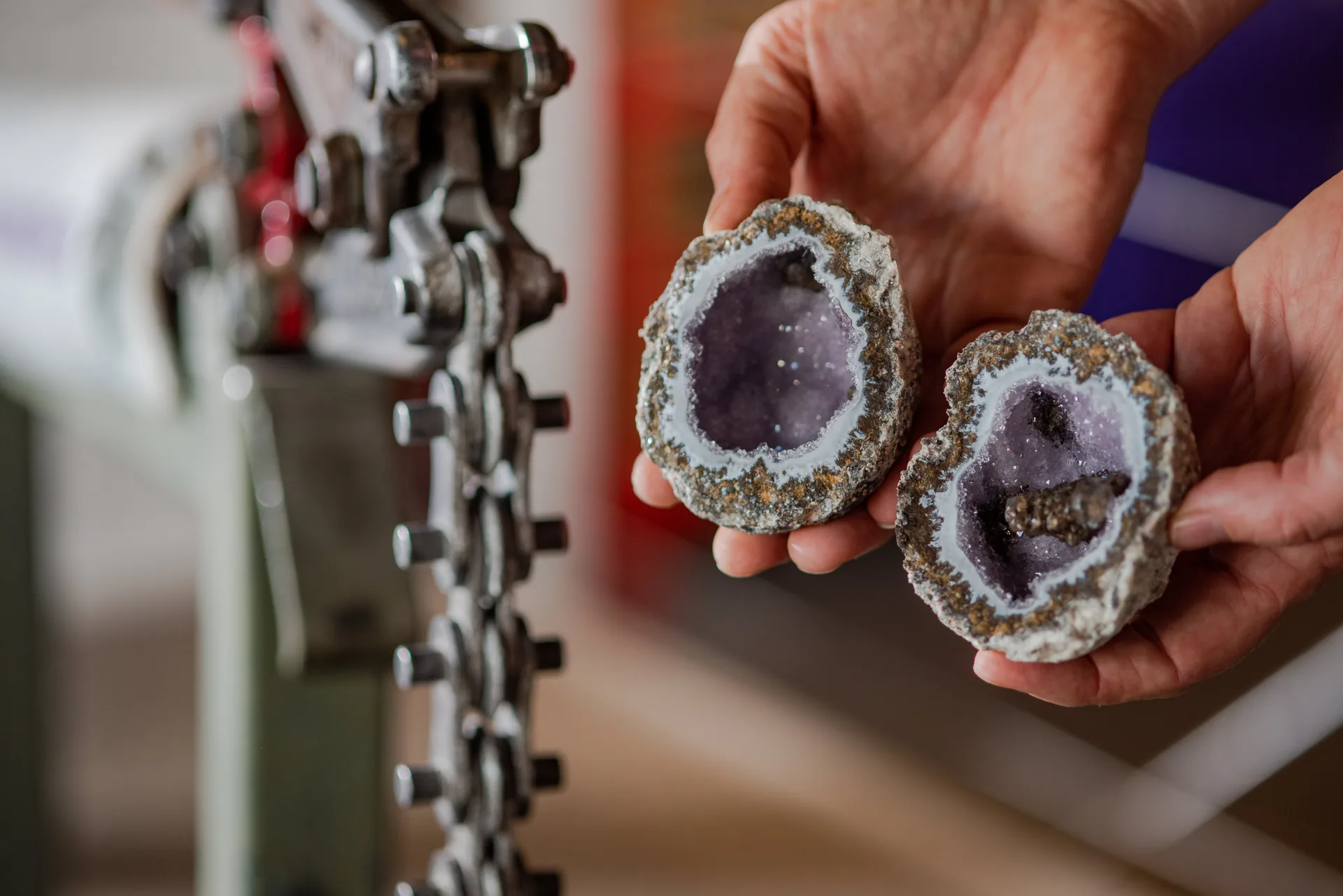 Hands holding two halves of a freshly cracked geode revealing amethyst crystals