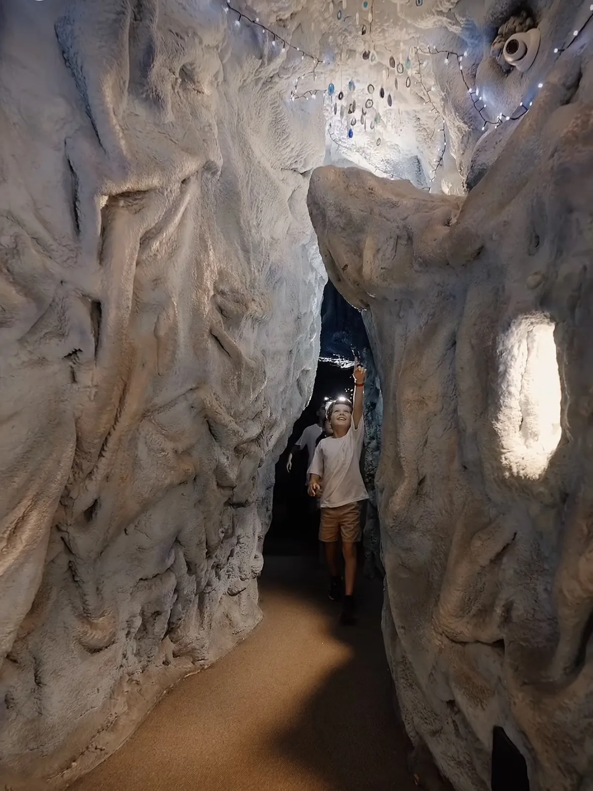 Reel: a young visitor with a headlamp exploring the cave passages
