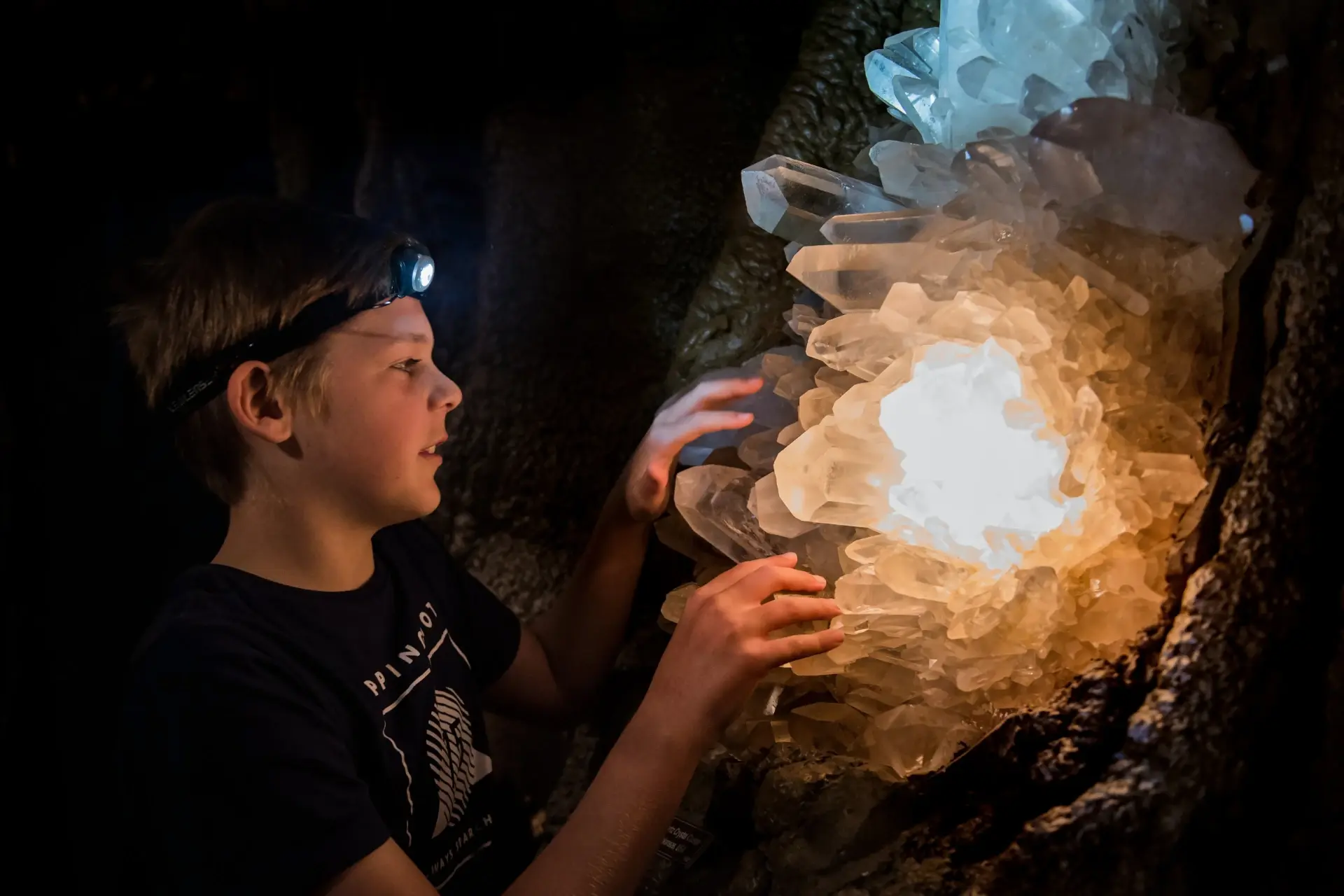 A child touching a glowing crystal formation inside the caves